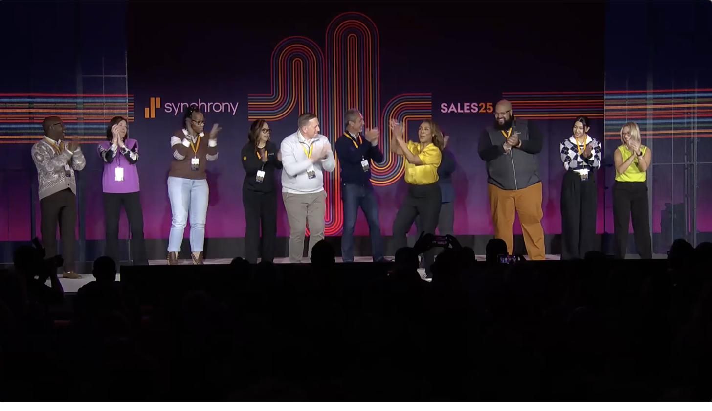 Attendees on stage applauding at the Synchrony Sales25 event